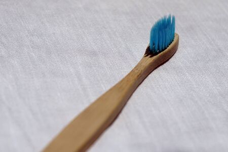 Close up of the Eco-friendly blue bamboo toothbrush on a white linen background. Natural organic...