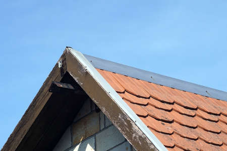 The roof of an old house with grunge tiles against the blue sky