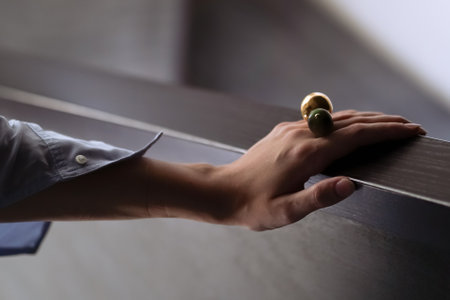 A woman's hand with ball rings on a brown wooden desk
