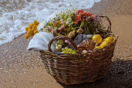 picnic basket at the seaside.  basket with fruits and flowers at the seashoreの写真素材
