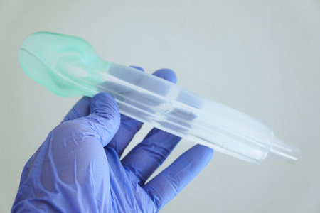 Hand in blue medical glove holding an I-gel supraglottic airway tube (size 3), medical equipment for anesthesia and emergency airway management.の写真素材