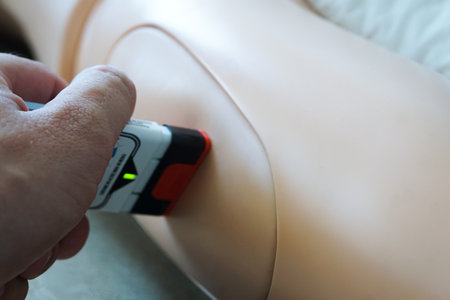 The use of an epinephrine auto-injector training device on a medical mannequin during a simulation exercise, demonstrating intramuscular epipen application for anaphylaxis and allergy first aid.の写真素材