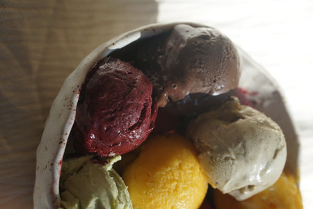 Close up of assorted colorful ice cream and sorbet scoops served in a rustic ceramic bowl on a wooden table: summer dessert, gourmet frozen treat, natural food, cafe or restaurant menu concept.の写真素材