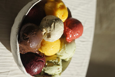 Close up of assorted colorful ice cream and sorbet scoops served in a rustic ceramic bowl on a wooden table: summer dessert, gourmet frozen treat, natural food, cafe or restaurant menu concept.の写真素材