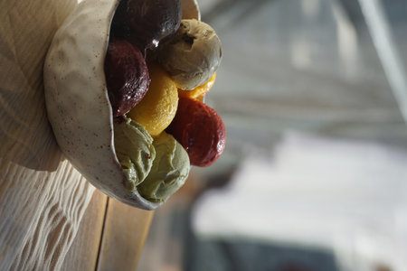 Close up of assorted colorful ice cream and sorbet scoops served in a rustic ceramic bowl on a wooden table: summer dessert, gourmet frozen treat, natural food, cafe or restaurant menu concept.の写真素材