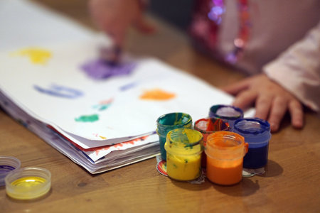 Child finger painting with bright colorful paints on paper during an art lesson or home activity. Early childhood creativity, fine motor skills, and the learning through play concept.の写真素材