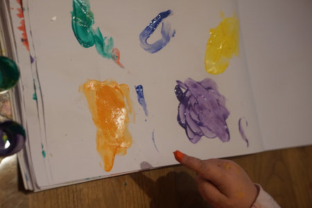 Child finger painting with bright colorful paints on paper during an art lesson or home activity. Early childhood creativity, fine motor skills, and the learning through play concept.の写真素材