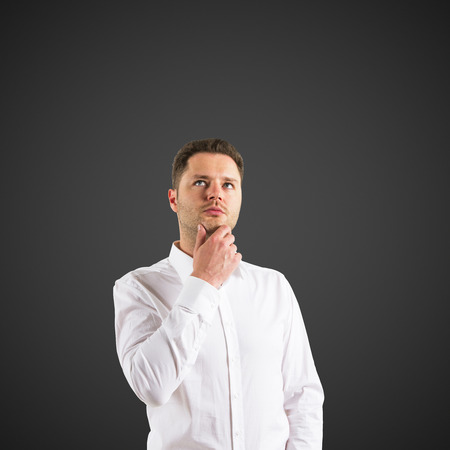 young handsome man thinking on black backgroundの写真素材