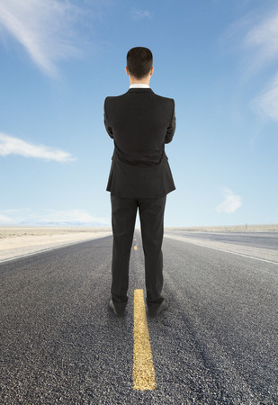 young businessman standing on road looking to horizontの写真素材