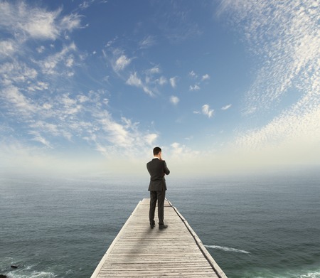 businessman standing on wooden pier and looking to skyの写真素材