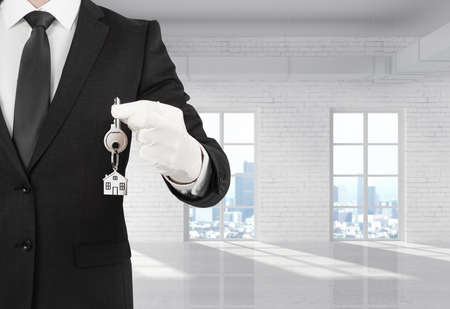 businessman holding a key standing in roomの写真素材