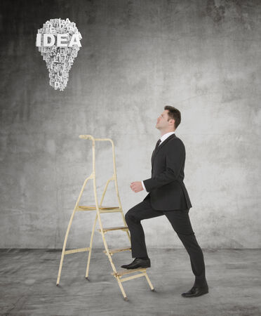 businessman climbing a ladder in roomの写真素材