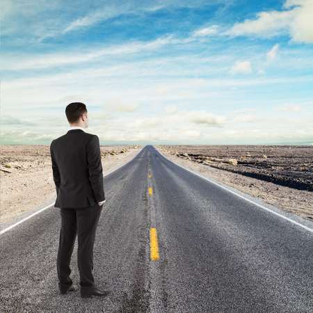 businessman standing on road looking to horizontの写真素材