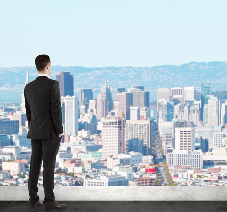businessman standing on roof and looking at cityの写真素材