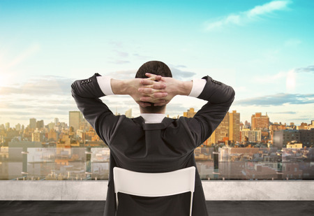 businessman sitting on roof and looking at cityの写真素材