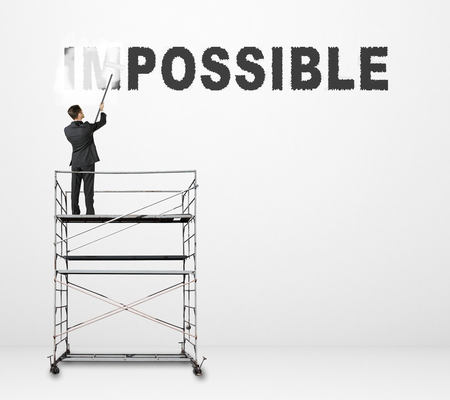 young businessman painting impossible text on wallの写真素材