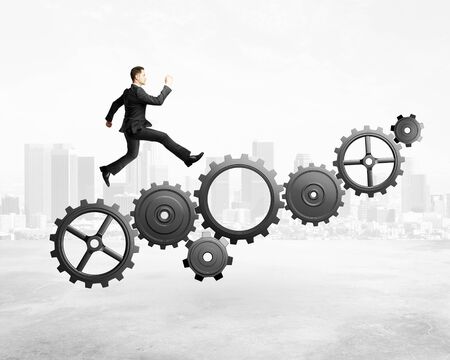 businessman runs on gears on city backgroundの写真素材