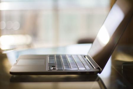 modern laptop on glass table at sunset, shallow depth of fieldの写真素材