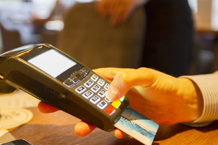 man's hand with credit card swipe through terminal