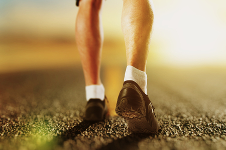 Runner legs on the road at sunrise, close upの写真素材