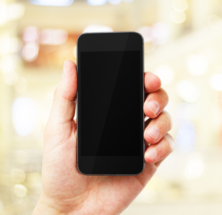 hand with empty cell phone on yellow backgroundの写真素材