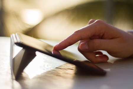 man clicks on digital tablet at sunriseの写真素材