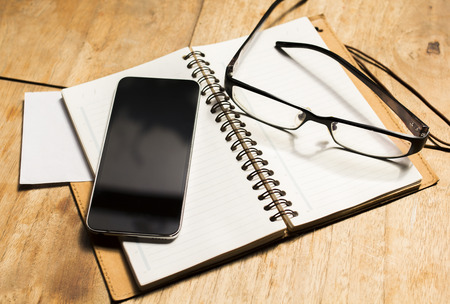 blank cell phone diary and glassesの写真素材