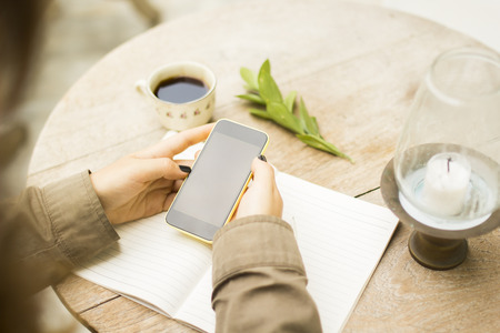 girl with blank cell phone, notebook and cup of coffeeの写真素材