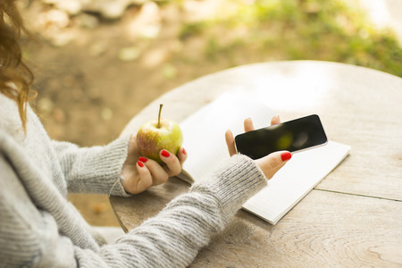 girl with cell phone, diary and green appleの写真素材