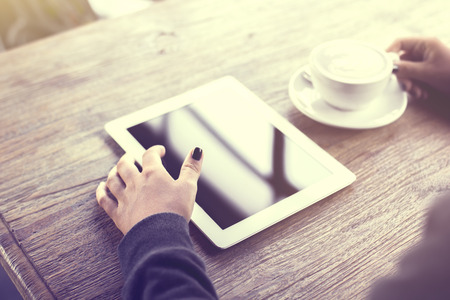 Girl using digital tablet and a cup of coffee on a wooden tableの写真素材