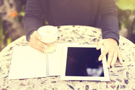 Girl using digital tablet, blank diary and coffee outdoor, vintage photo effect