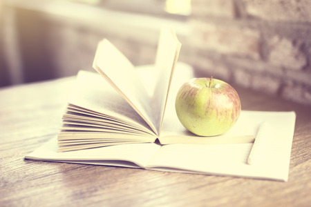 Book, apple and blank diary on a wooden tableの写真素材