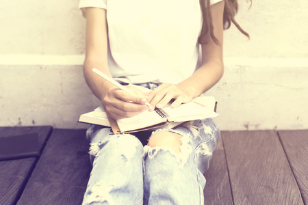 Schoolgirl sitting on floor and wrote in a diaryの写真素材