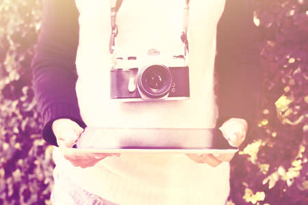 Girl with digital tablet and old photo camera, vintage color effect