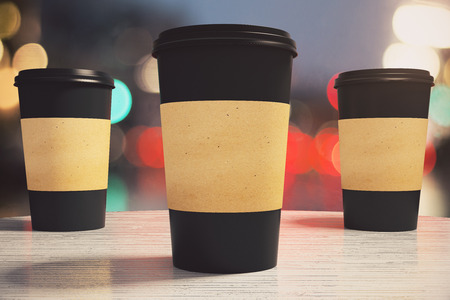 three black paper coffee cup on a table in a cafe, mock upの写真素材