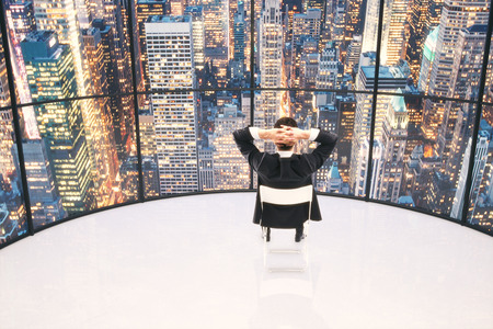 Businessman looking to the city at evening in an empty white roomの写真素材