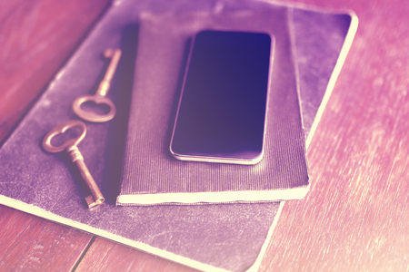 Blank smartphone with diary and old style keys on wooden floorの写真素材