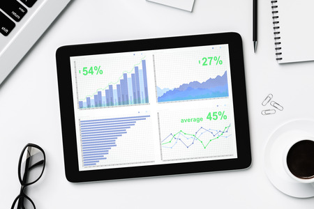 Business charts on digital tablet screen with glasses and cup of coffeeの写真素材