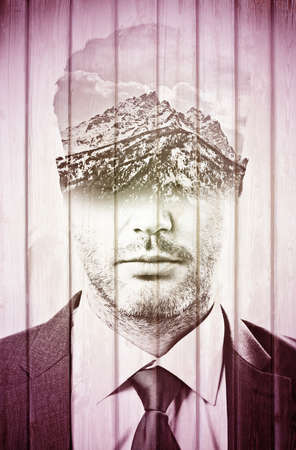 Double explosure with businessman face and mountains with the skyの写真素材