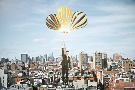 Businessman with baloons above megapolis city conceptの写真素材