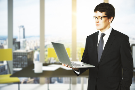 Businessman with laptop in modern officeの写真素材