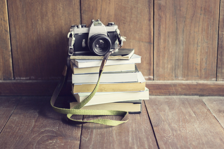 Old style camera on pile of books on wooden floorの写真素材