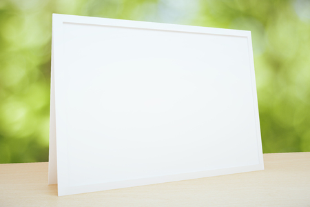 Blank picture frame on the table at foliage background, mock upの写真素材