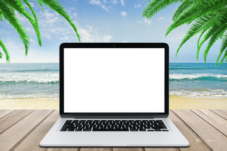 Blank white laptop screen on wooden bench at beach backgroundの写真素材