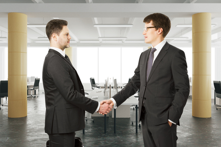 Business partners shake their hands in modern open space officeの写真素材