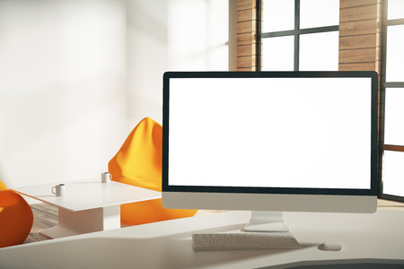 Blank white computer screen in sunny loft office, mock upの写真素材