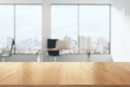 Wooden table in sunny office with big windowsの写真素材