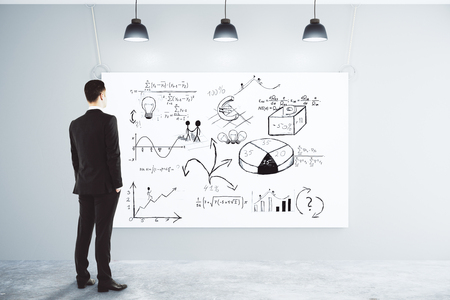 Businessman looking at the poster with business scheme concept on the wall in empty loft roomの写真素材