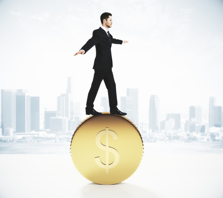 Businessman balancing on a gold coinの写真素材