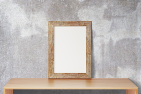 Blank wooden picture frame standing on the wooden table on a background of a concrete wall, mock upの写真素材